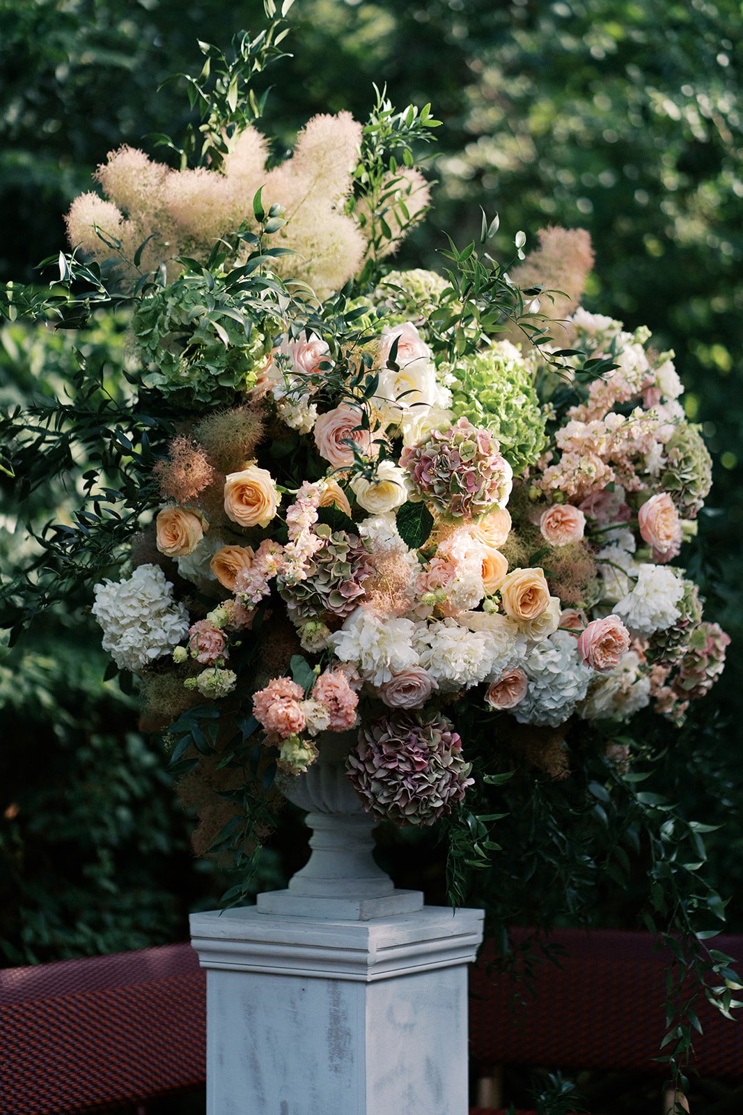 Composition florale de mariage sur colonne avec roses pêche, hortensias et feuillages